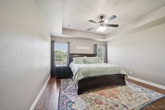 921 S 75th St, Broken Arrow, OK 74014 - bedroom with a textured wall, wood finished floors, a tray ceiling, ceiling fan, and a textured ceiling