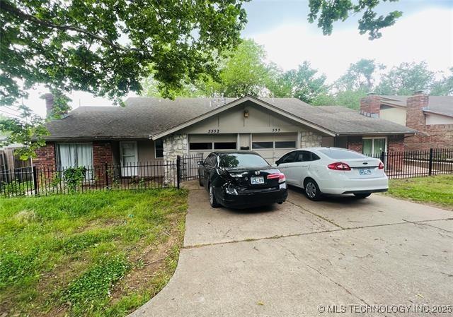 5550 S Lewis Ct, Tulsa, OK 74105 - view of front of property featuring concrete driveway, a garage, a chimney, brick siding, and a fenced front yard