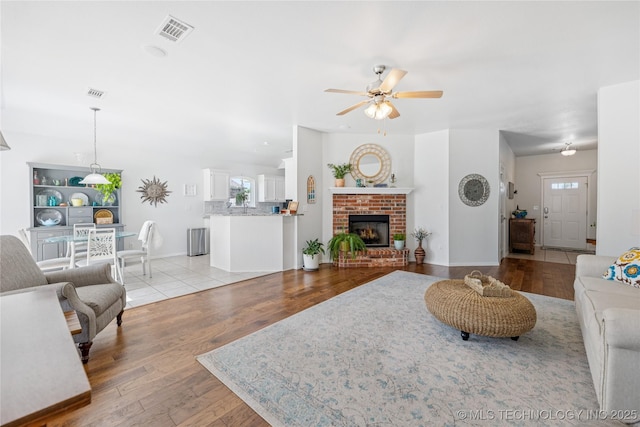 14907 E 88th St N, Owasso, OK 74055 - living room with ceiling fan, light wood-style floors, and a brick fireplace