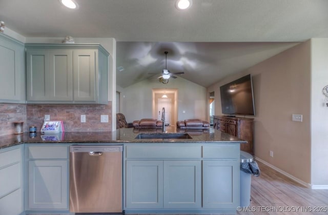 12005 E 108th Pl N, Owasso, OK 74055 - kitchen with stainless steel dishwasher, light wood finished floors, dark stone counters, a ceiling fan, and tasteful backsplash