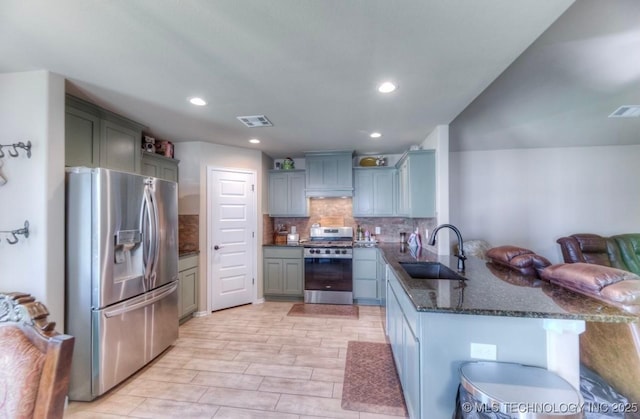 12005 E 108th Pl N, Owasso, OK 74055 - kitchen featuring stainless steel appliances, a peninsula, open floor plan, dark stone countertops, and tasteful backsplash