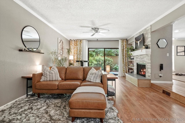 2955 E 84th St S Unit 65, Tulsa, OK 74137 - living area with crown molding, a textured ceiling, ceiling fan, wood finished floors, and a large fireplace