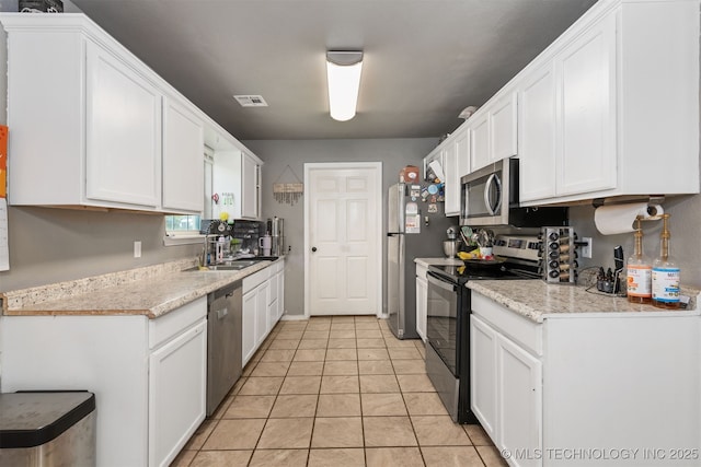 802 NE 9th St, Wagoner, OK 74467 - kitchen with appliances with stainless steel finishes, white cabinetry, light countertops, and light tile patterned flooring