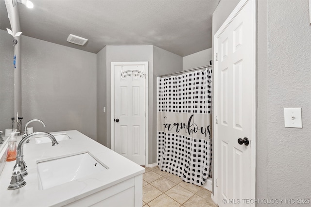 802 NE 9th St, Wagoner, OK 74467 - full bath featuring tile patterned floors, double vanity, curtained shower, a textured ceiling, and a textured wall