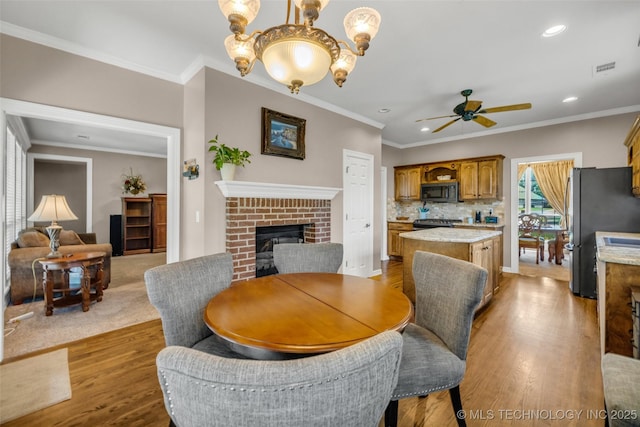 13804 E 90th St, Owasso, OK 74055 - dining area with a fireplace, ceiling fan, wood finished floors, ornamental molding, and recessed lighting