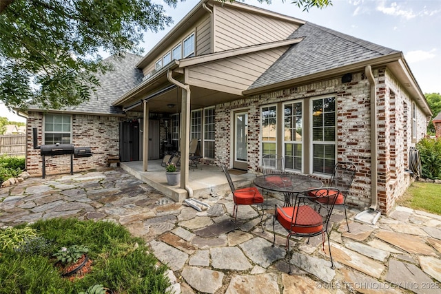 13804 E 90th St, Owasso, OK 74055 - rear view of house featuring roof with shingles, a patio area, brick siding, and outdoor dining space