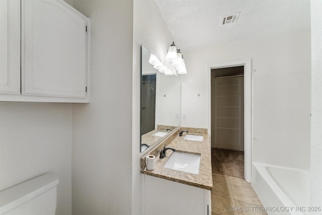 8973 N Crestwood Dr, Sperry, OK 74073 - bathroom featuring tile patterned flooring, double vanity, a textured ceiling, and a bathtub