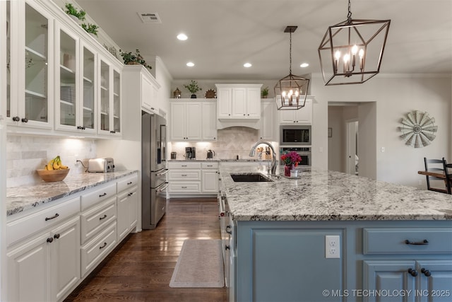 22322 E 121st St S, Broken Arrow, OK 74014 - kitchen with stainless steel appliances, a chandelier, white cabinetry, dark wood-style floors, and ornamental molding