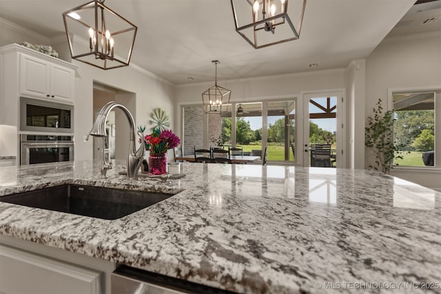 22322 E 121st St S, Broken Arrow, OK 74014 - kitchen featuring a chandelier, oven, light stone counters, built in microwave, and white cabinetry