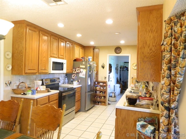 399987 W 3700th Rd, Ramona, OK 74061 - kitchen with stainless steel appliances, light countertops, light tile patterned flooring, recessed lighting, and decorative backsplash