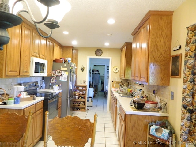 399987 W 3700th Rd, Ramona, OK 74061 - kitchen featuring white microwave, black range with electric cooktop, backsplash, light tile patterned floors, and light countertops