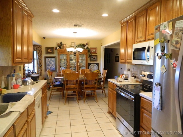 399987 W 3700th Rd, Ramona, OK 74061 - kitchen featuring stainless steel appliances, brown cabinetry, decorative backsplash, light countertops, and a textured ceiling