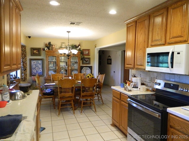 399987 W 3700th Rd, Ramona, OK 74061 - kitchen with white microwave, stainless steel range with electric stovetop, brown cabinetry, light countertops, and recessed lighting