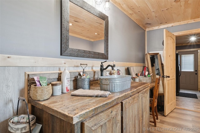 719 Oklahoma Ave, Wynona, OK 74084 - bar area featuring wooden ceiling, light wood-style floors, and a wainscoted wall