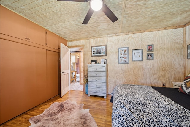 719 Oklahoma Ave, Wynona, OK 74084 - bedroom with wood ceiling, wooden walls, light wood-style floors, ceiling fan, and a closet