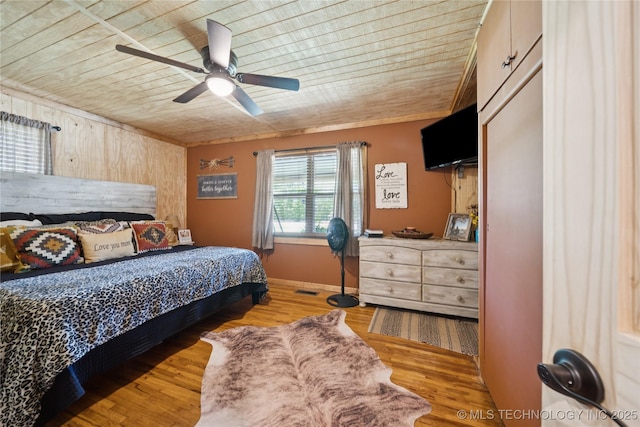 719 Oklahoma Ave, Wynona, OK 74084 - bedroom with wooden ceiling, wood finished floors, a ceiling fan, and wood walls