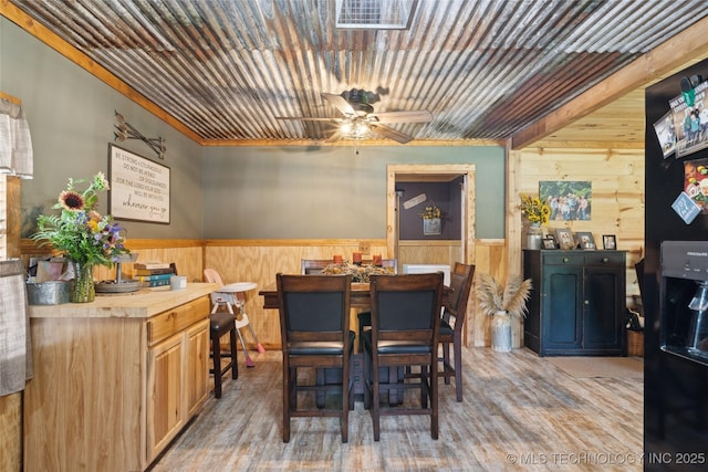 719 Oklahoma Ave, Wynona, OK 74084 - dining area with wooden walls, wood finished floors, a ceiling fan, and a wainscoted wall