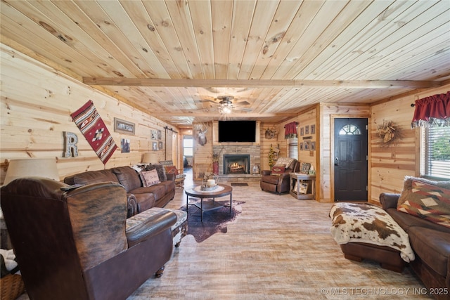 719 Oklahoma Ave, Wynona, OK 74084 - living room featuring a wooden ceiling with exposed beams, wood walls, ceiling fan, a stone fireplace, and wood finished floors
