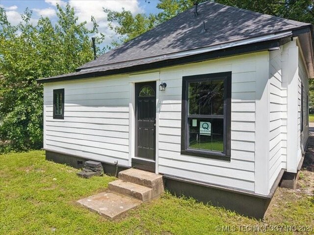 409 N Cherokee St, Claremore, OK 74017 - back of property with entry steps, roof with shingles, and a yard