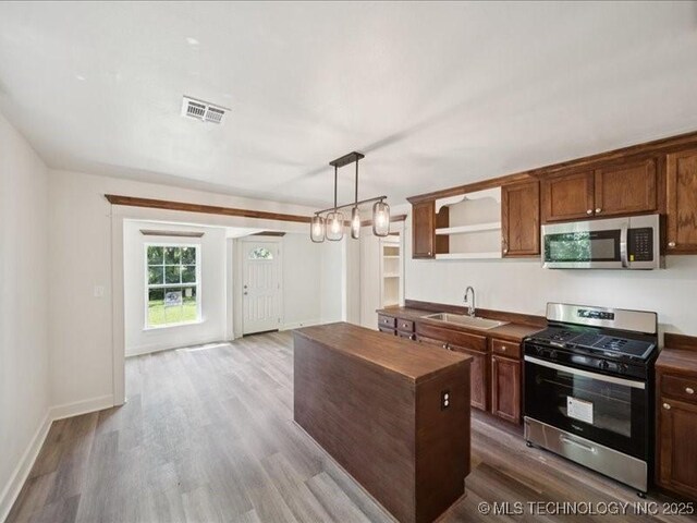 409 N Cherokee St, Claremore, OK 74017 - kitchen featuring appliances with stainless steel finishes, wood counters, open shelves, a center island, and wood finished floors