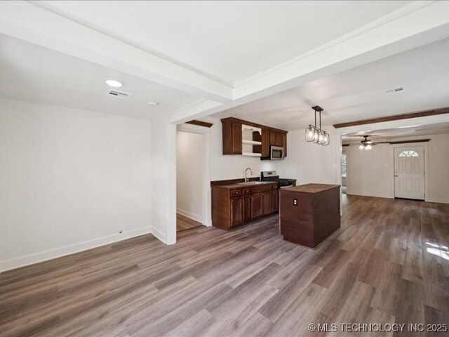 409 N Cherokee St, Claremore, OK 74017 - kitchen with stainless steel microwave, ceiling fan, wood finished floors, open floor plan, and dark brown cabinets