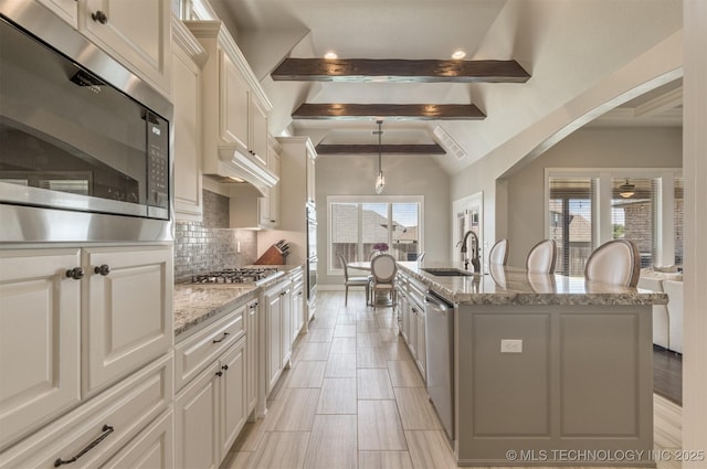 449 E 129th Pl, Jenks, OK 74037 - kitchen with appliances with stainless steel finishes, tasteful backsplash, arched walkways, hanging light fixtures, and light stone counters