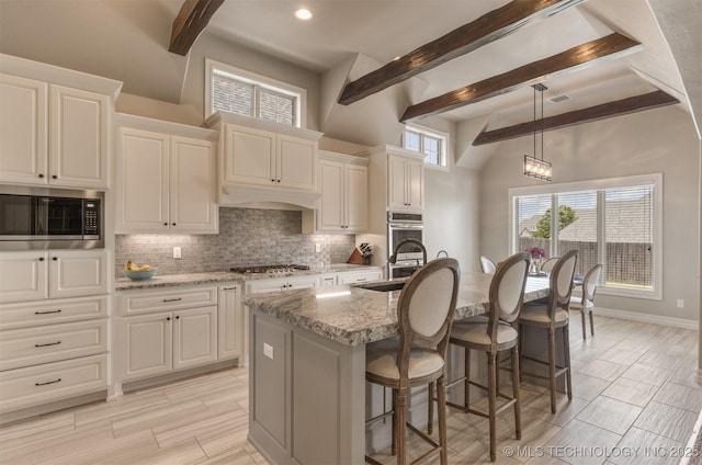 449 E 129th Pl, Jenks, OK 74037 - kitchen with stainless steel appliances, decorative backsplash, a breakfast bar area, light stone countertops, and a center island with sink