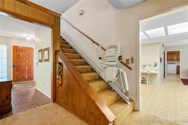 7033 E 99th St, Tulsa, OK 74133 - staircase with washer / clothes dryer, brick floors, wood walls, and a textured ceiling