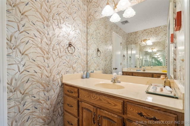 7033 E 99th St, Tulsa, OK 74133 - bathroom with wallpapered walls, vanity, and a chandelier