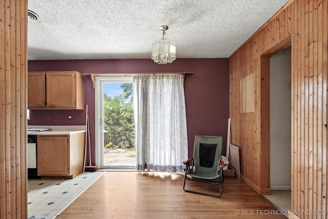 705 W Hartford Pl, Broken Arrow, OK 74012 - unfurnished dining area with light wood finished floors, a chandelier, a textured ceiling, and wood walls