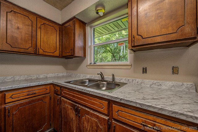 807 E Tahlequah, Sulphur, OK 73086 - kitchen featuring a textured wall, light countertops, and brown cabinets