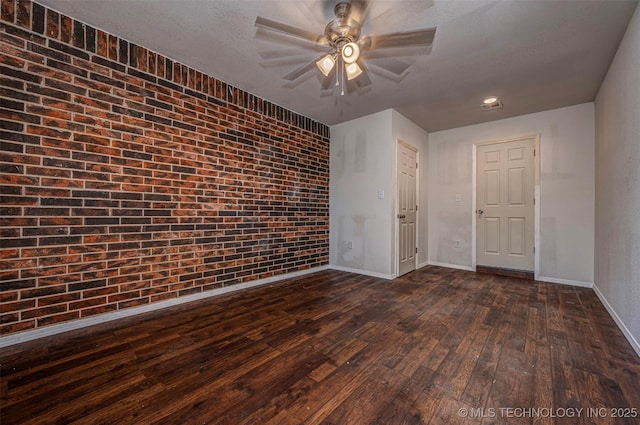 807 E Tahlequah, Sulphur, OK 73086 - spare room featuring dark wood-style flooring, a ceiling fan, and brick wall
