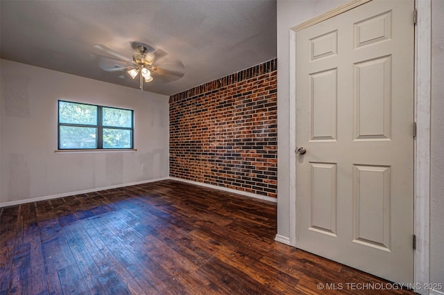 807 E Tahlequah, Sulphur, OK 73086 - spare room with brick wall, ceiling fan, and dark wood-style floors