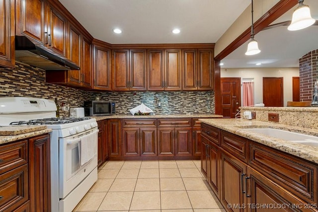 12915 S 120th E Pl, Tulsa, OK 74011 - kitchen with gas range gas stove, under cabinet range hood, tasteful backsplash, light tile patterned floors, and recessed lighting