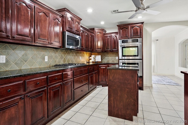 13718 S 262nd E Ave, Coweta, OK 74429 - kitchen with dark brown cabinets, appliances with stainless steel finishes, arched walkways, ceiling fan, and tasteful backsplash