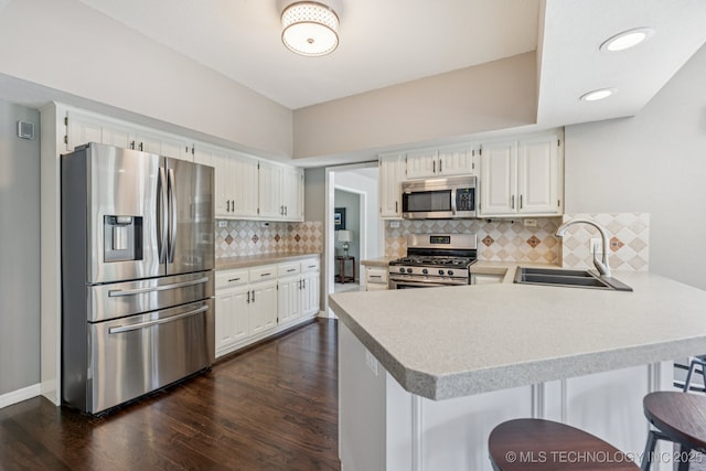 200 N Redwood Ct, Broken Arrow, OK 74012 - kitchen with appliances with stainless steel finishes, a peninsula, dark wood finished floors, light countertops, and white cabinetry