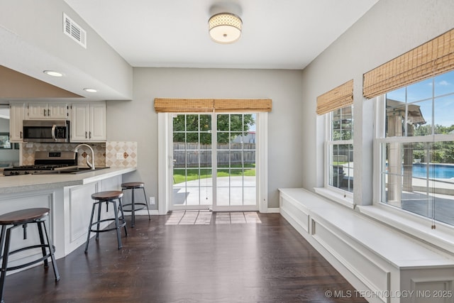200 N Redwood Ct, Broken Arrow, OK 74012 - kitchen with appliances with stainless steel finishes, a kitchen breakfast bar, tasteful backsplash, dark wood-style flooring, and light countertops