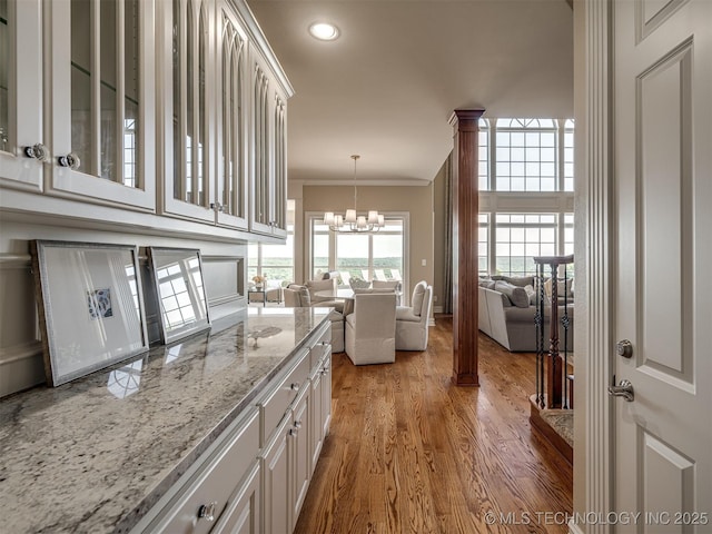 34159 E 698th Rd, Wagoner, OK 74467 - kitchen featuring glass insert cabinets, wood finished floors, a chandelier, open floor plan, and light stone counters