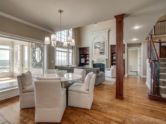 34159 E 698th Rd, Wagoner, OK 74467 - dining room with ornamental molding, a chandelier, a glass covered fireplace, light wood-style floors, and stairway