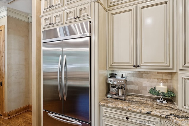19735 E Woodhaven Rd, Owasso, OK 74055 - kitchen with built in fridge, cream cabinetry, tasteful backsplash, light stone counters, and wood finished floors