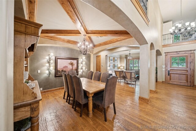 19735 E Woodhaven Rd, Owasso, OK 74055 - dining space featuring a chandelier, arched walkways, light wood finished floors, and beam ceiling