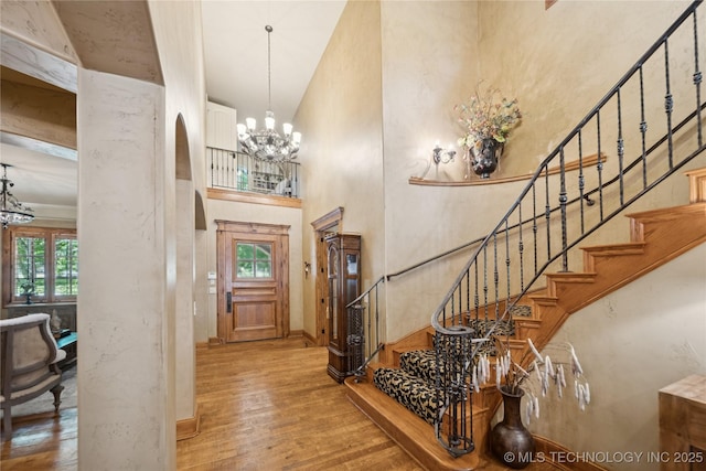 19735 E Woodhaven Rd, Owasso, OK 74055 - foyer featuring a towering ceiling, a chandelier, hardwood / wood-style floors, stairway, and arched walkways