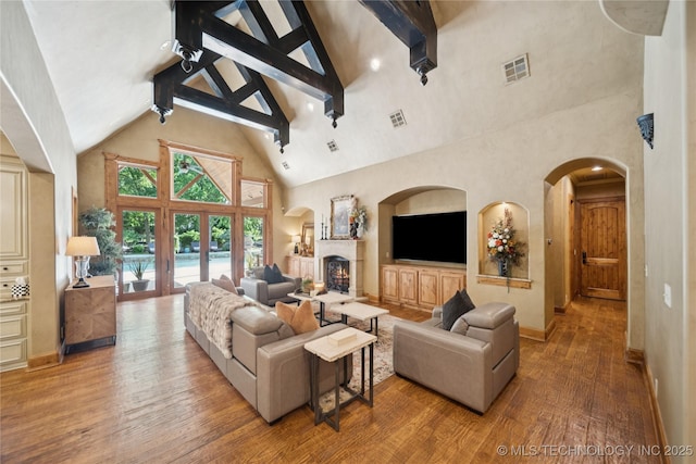 19735 E Woodhaven Rd, Owasso, OK 74055 - living room with high vaulted ceiling, wood-type flooring, a warm lit fireplace, arched walkways, and beam ceiling