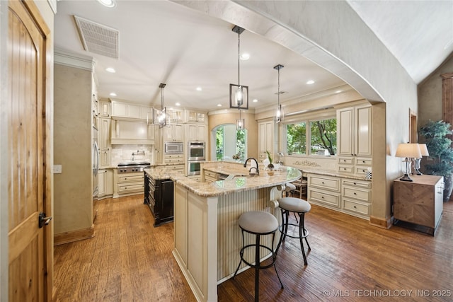 19735 E Woodhaven Rd, Owasso, OK 74055 - kitchen with cream cabinetry, stainless steel appliances, a large island, wood finished floors, and recessed lighting