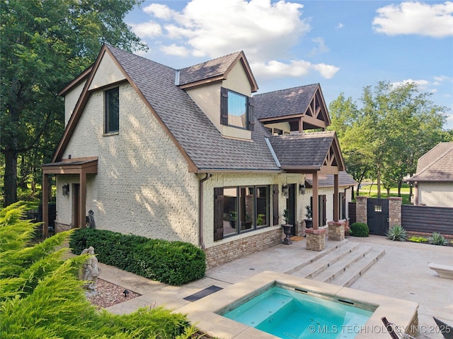 19735 E Woodhaven Rd, Owasso, OK 74055 - back of property with a patio, an in-ground hot tub, a shingled roof, and brick siding