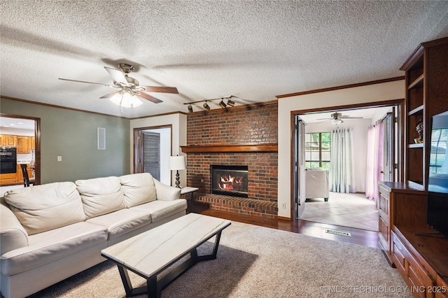 7222 E 87th St, Tulsa, OK 74133 - living room featuring ceiling fan, a brick fireplace, crown molding, a textured ceiling, and rail lighting