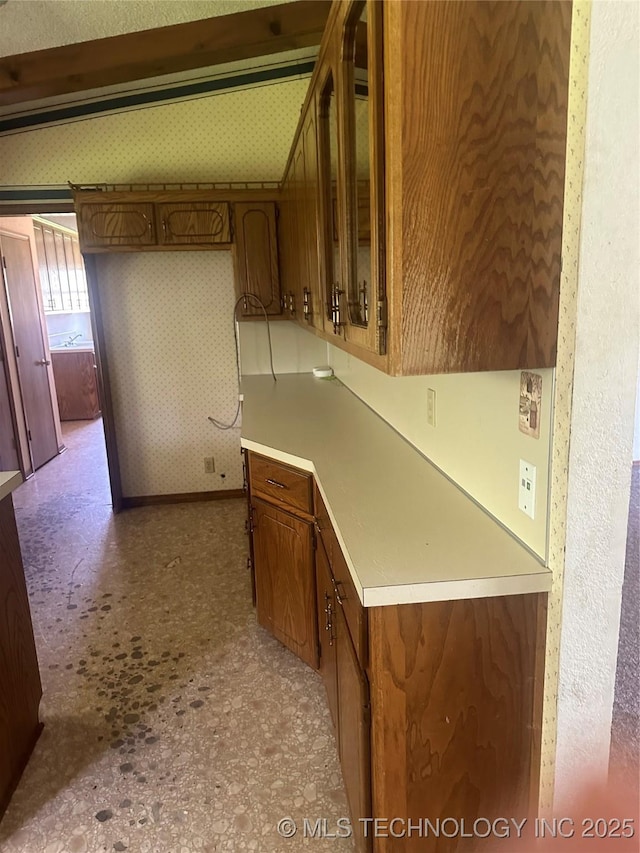 282 Westland Rd, Sapulpa, OK 74066 - kitchen featuring light countertops, glass insert cabinets, brown cabinets, and wallpapered walls