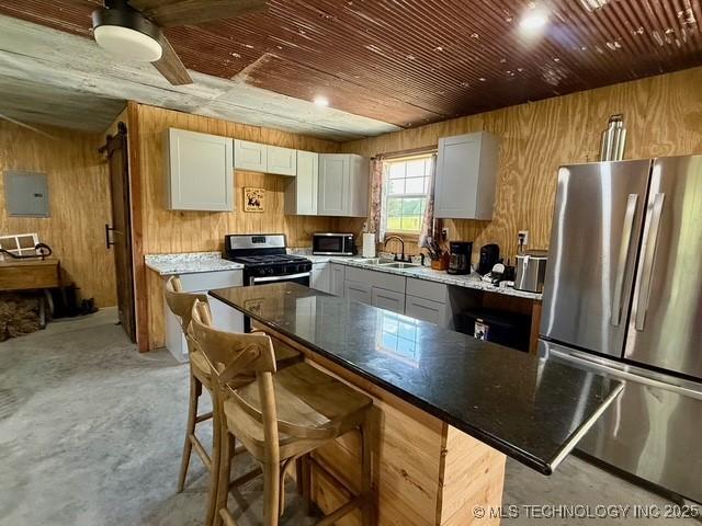 105148 S 4500, Vian, OK 74962 - kitchen with appliances with stainless steel finishes, wood walls, concrete flooring, electric panel, and a kitchen breakfast bar