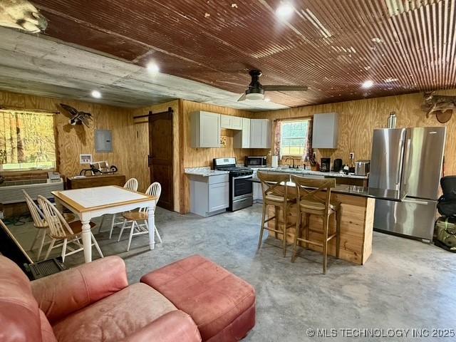 105148 S 4500, Vian, OK 74962 - kitchen featuring stainless steel appliances, wooden walls, concrete flooring, a ceiling fan, and a kitchen island
