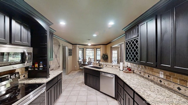 6166 Hedges St, Ardmore, OK 73401 - kitchen with appliances with stainless steel finishes, ornamental molding, backsplash, dark cabinetry, and a peninsula